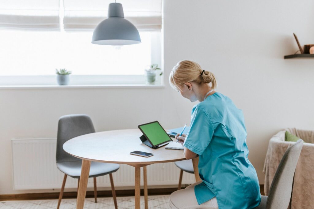 Female nurse working with digital tablet at home